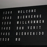 Auf einer Anzeigentafel steht "Willkommen" auf verschiedenen Sprachen.