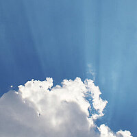 Wolken auf einem blauen Himmel von Sonnenstrahlen durchbrochen 