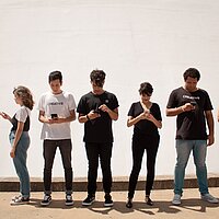 6 Jugendliche stehen in einer Reihe vor einer weißen Wand ohne sich anzuschauen. Alle schauen in ihr Handy. 