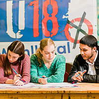 Fünf Jugendliche sitzen am Tisch und informieren sich über die Parteiinhalte.