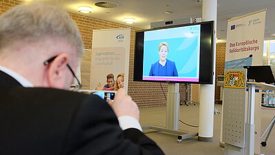 Im Hintergrund hält die ehemalige Bundesfamilienministerin Giffey eine Videoansprache. 