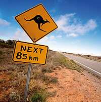 gelbes Schild mit einem Känguru-Symbol und mit der Angabe unterhalb Next 85 km; in der Mitte eine Straße verliert sich in die Ferne