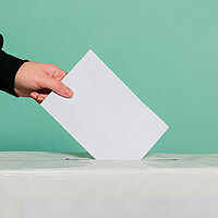 ein Stimmzettel wird in eine U18-Wahlurne geworfen