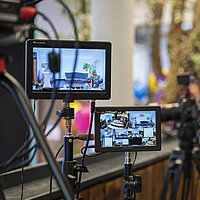 Mehrere Bildschirme von Kameras, die einen Veranstaltungsraum filmen