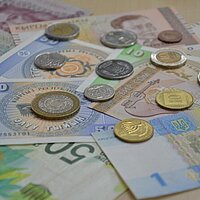 Geldscheine und Münzen von verschiedenen Währungen liegen auf einem Tisch. 