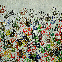 Auf einer Wand sind viele verschiedene bunte Handabdrücke